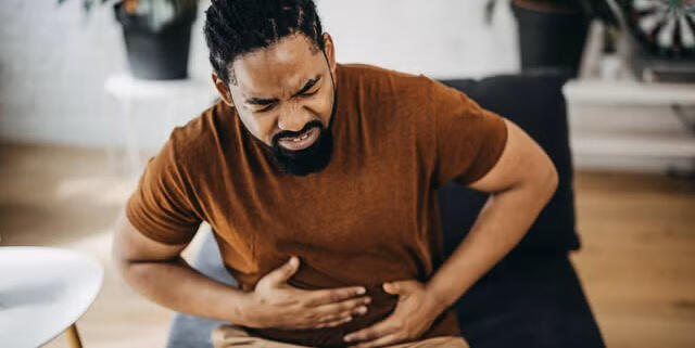 digestive-discomfort-men-over-40 Middle-aged man experiencing mild digestive discomfort and bloating at home